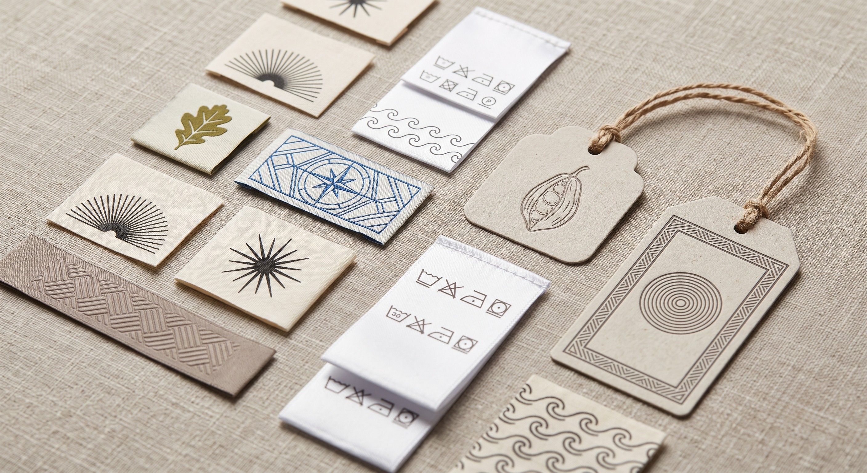  Close-up flat lay of custom clothing branding items, including woven labels, care labels, and cardboard hang tags.