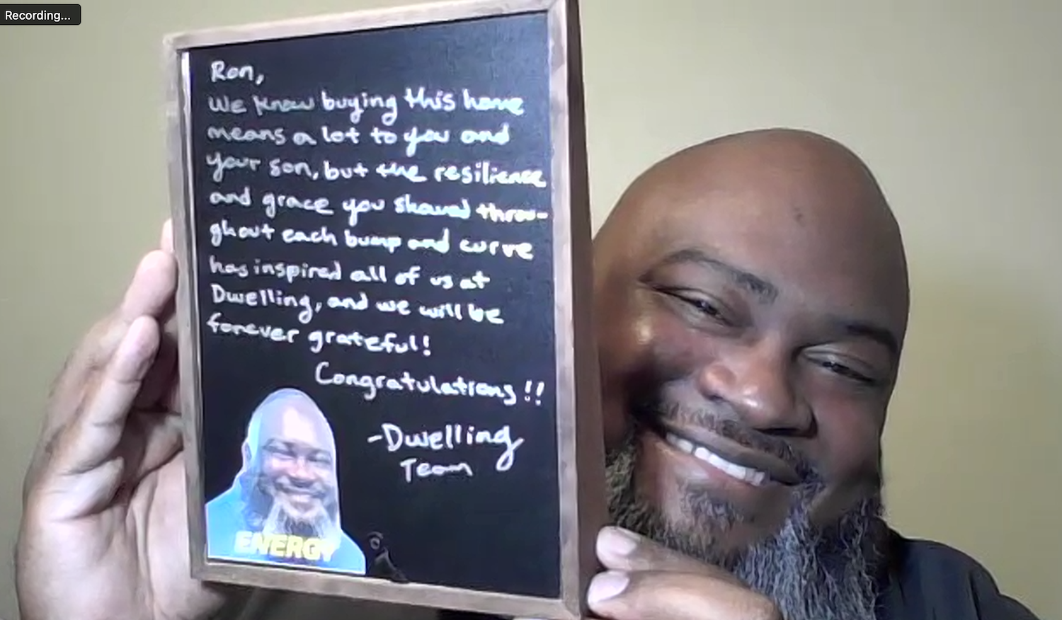 Photo of Ron holding a frame with a personal message from the Dwelling team.