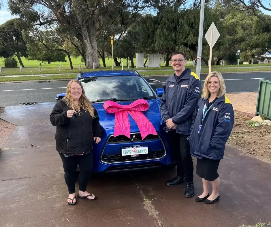 A woman shows off her new car keys next to a car and two easyauto123 team members