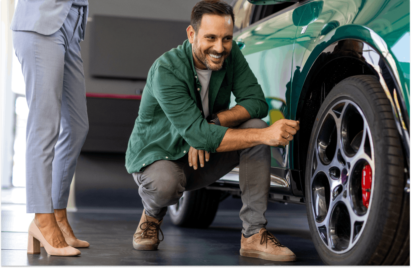 Man checking wheels of new car in a showroom