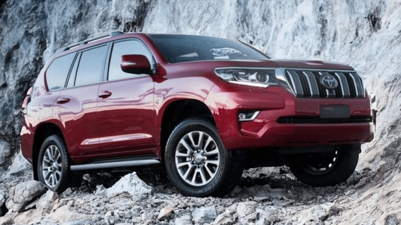 red toyota prado driving on rocks