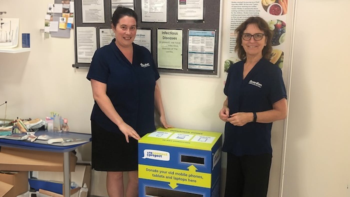 Reconnect Project volunteers standing by an electronics donation bin.