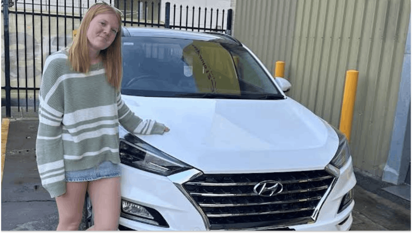 Image of young woman with a white Hyundai car that she has just bought for easyauto123