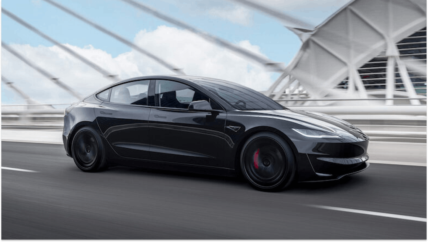 Black Tesla driving across city bridge