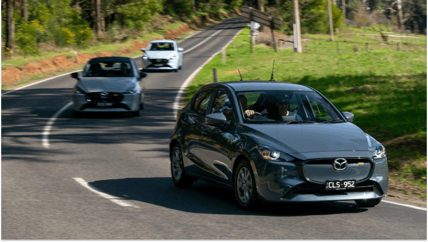 Three Mazda 2 hatchbacks driving in convoy on a country road