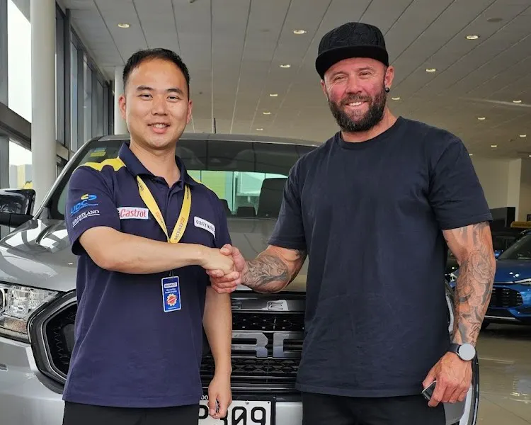 Man in easyauto123 uniform shakes hand of another man in front of a vehicle that's been purchased