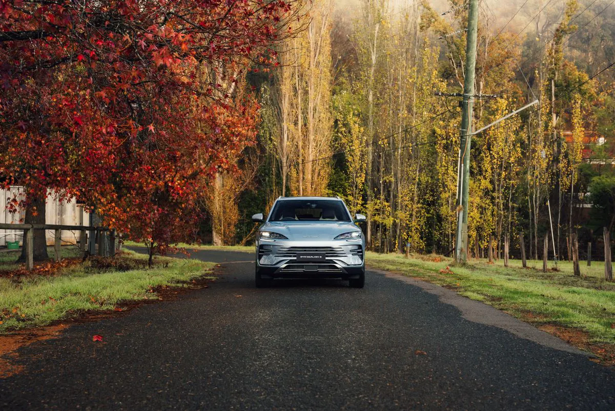 Electric vehicle driving on a country road during autumn