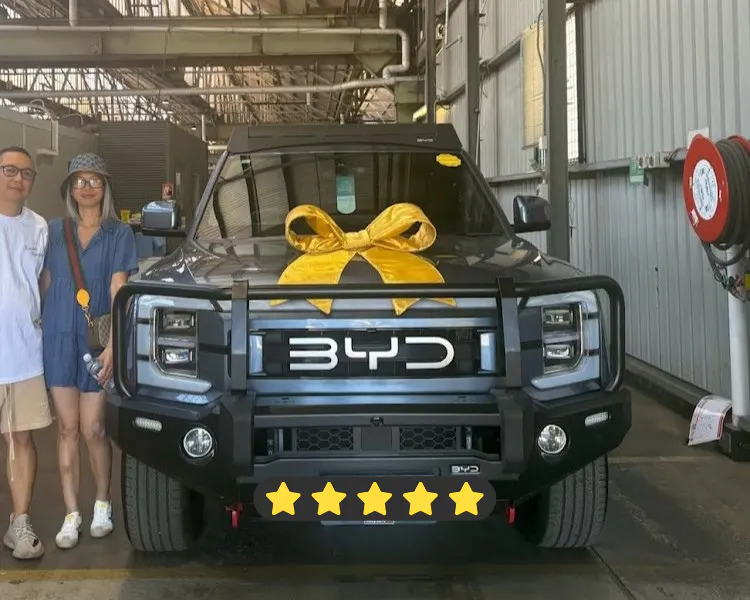 Happy couple standing next to a newly purchased used BYD Shark