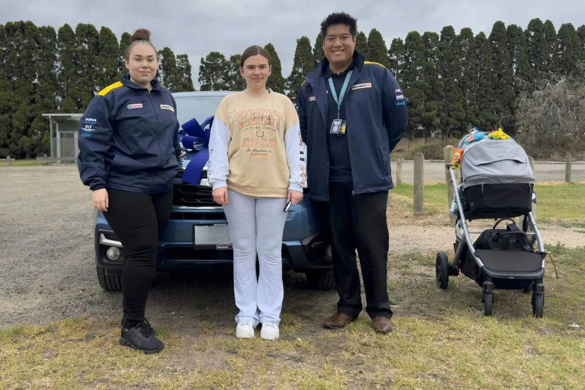 A young mum stands in front of a vehicle alongside two easyauto123 used car salespeople
