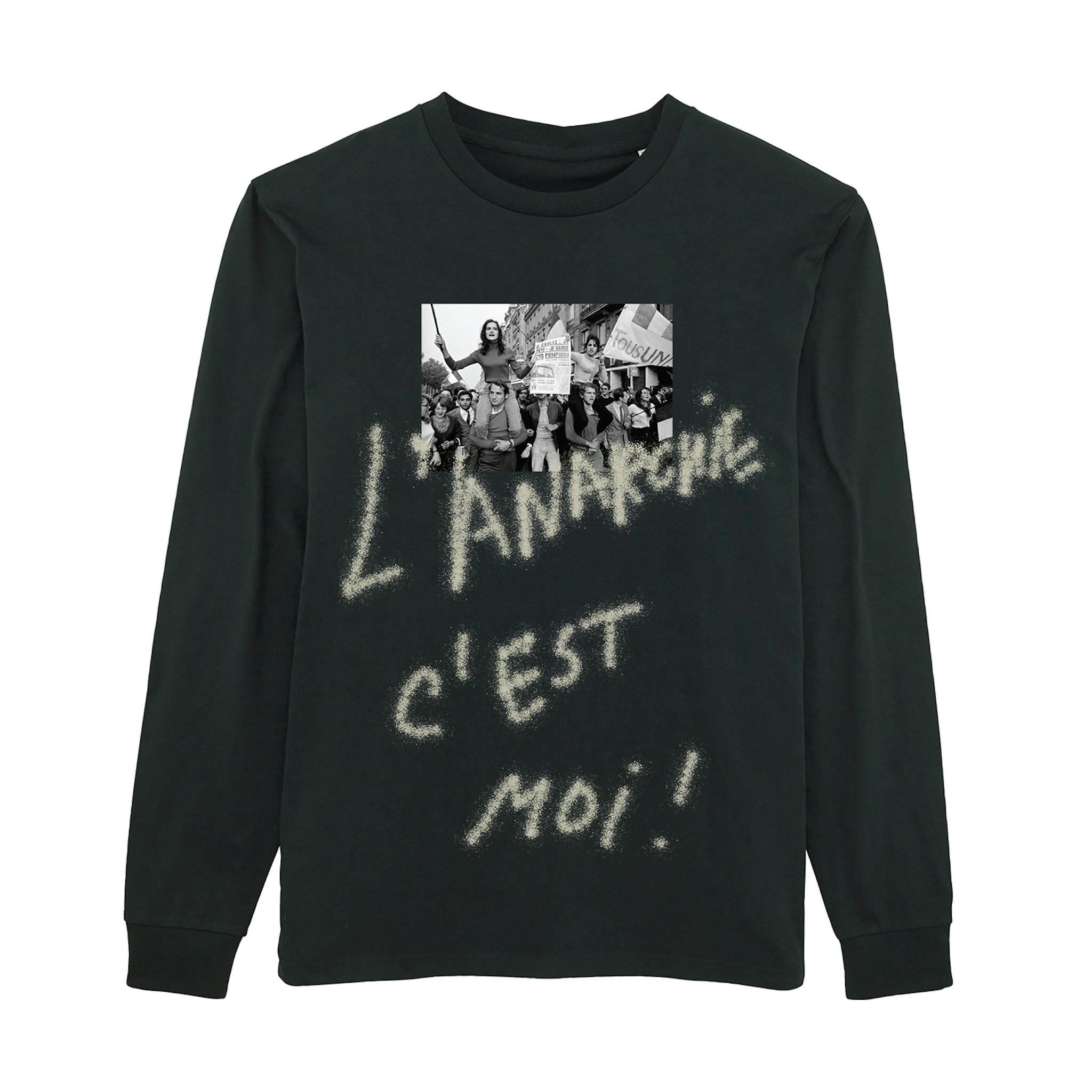 A dark long-sleeve T-shirt featuring a central photograph with protesters, above which is written in large, chalk-style lettering "L'ANARCHIE C'EST MOI!"