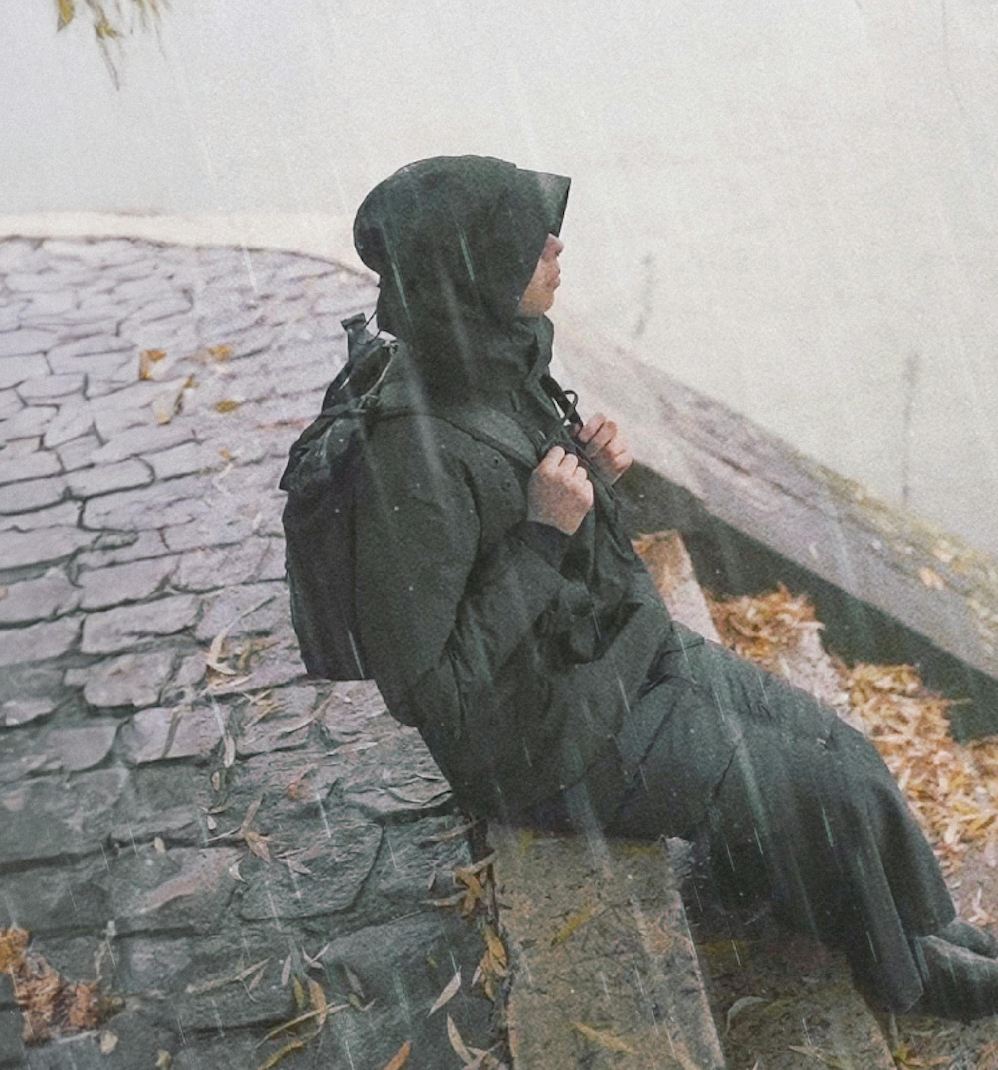 A woman sitting on stone steps in the rain