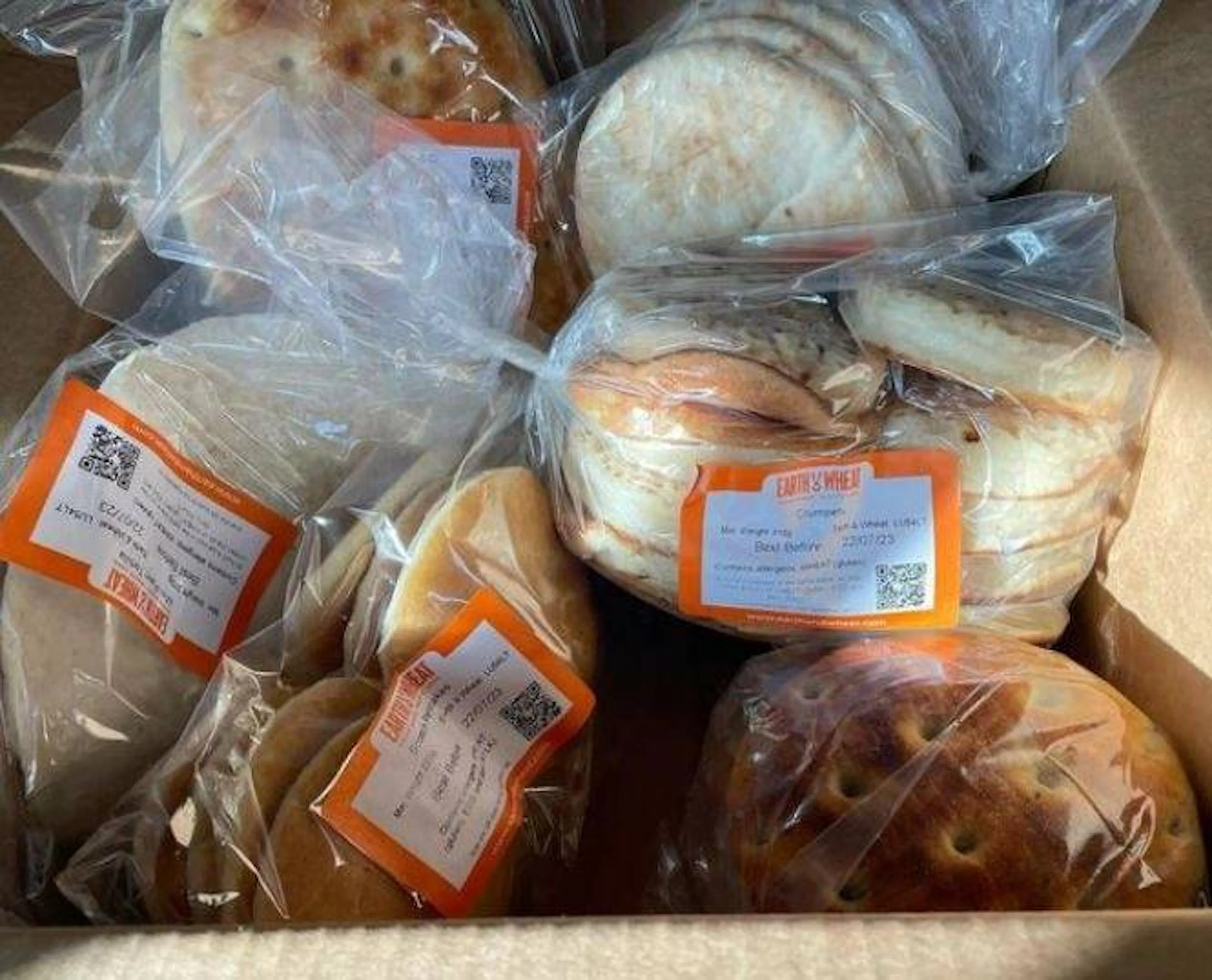 Customer image of contents of a box delivery. Packaged bread options in box.
