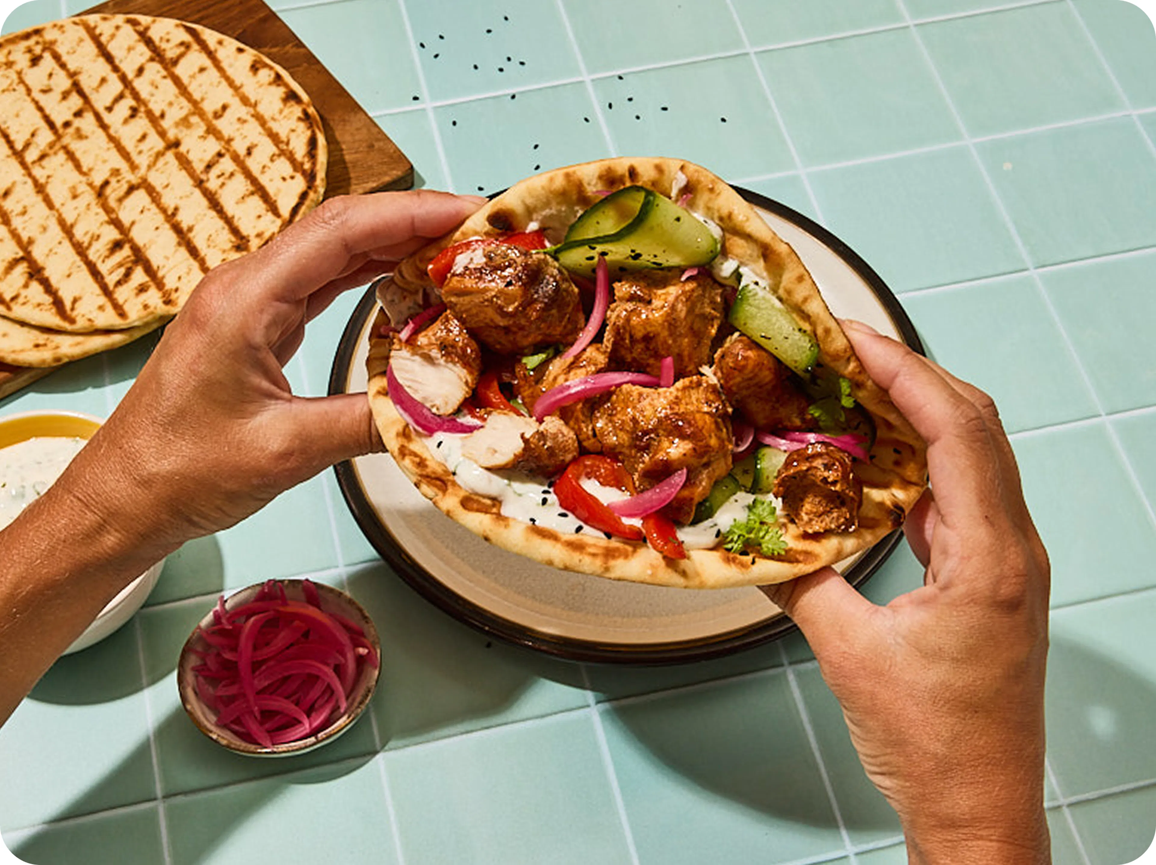 A person holding freshly baked Earth & Wheat pitta bread sandwich with a sumptous meaty filling