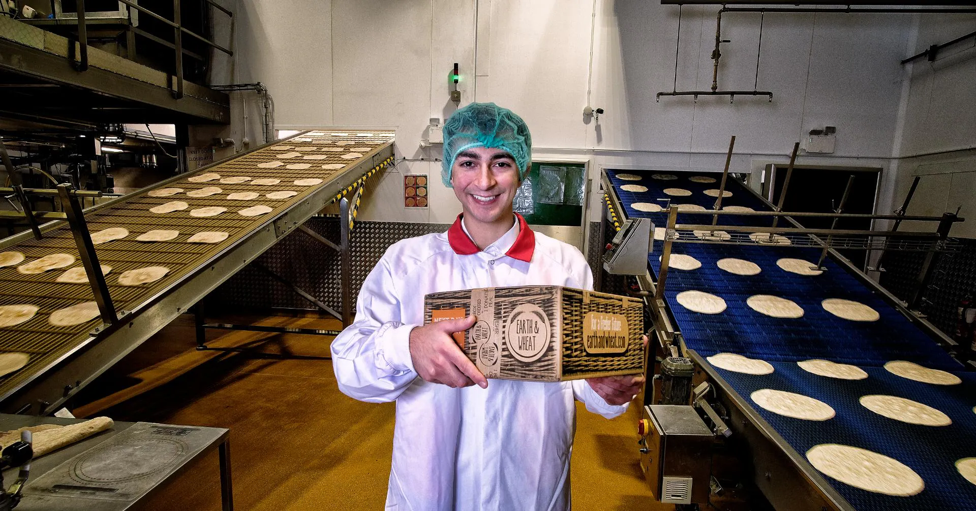 Founder of Earth & Wheat in bakery holding a bread bread box at first launch