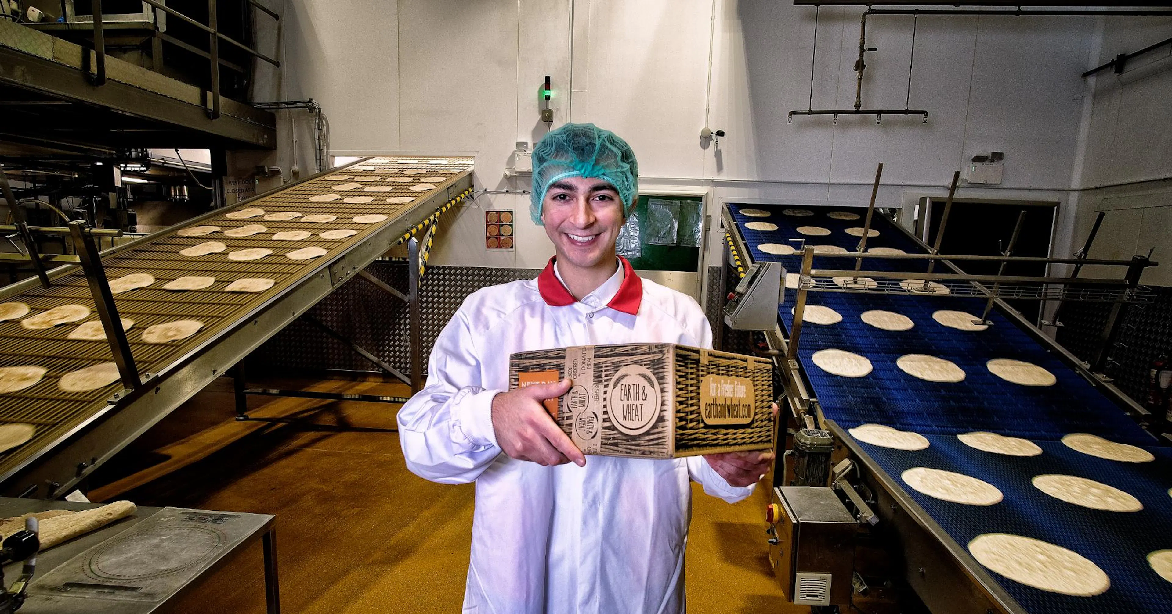 Founder of Earth & Wheat in bakery holding a bread bread box at first launch