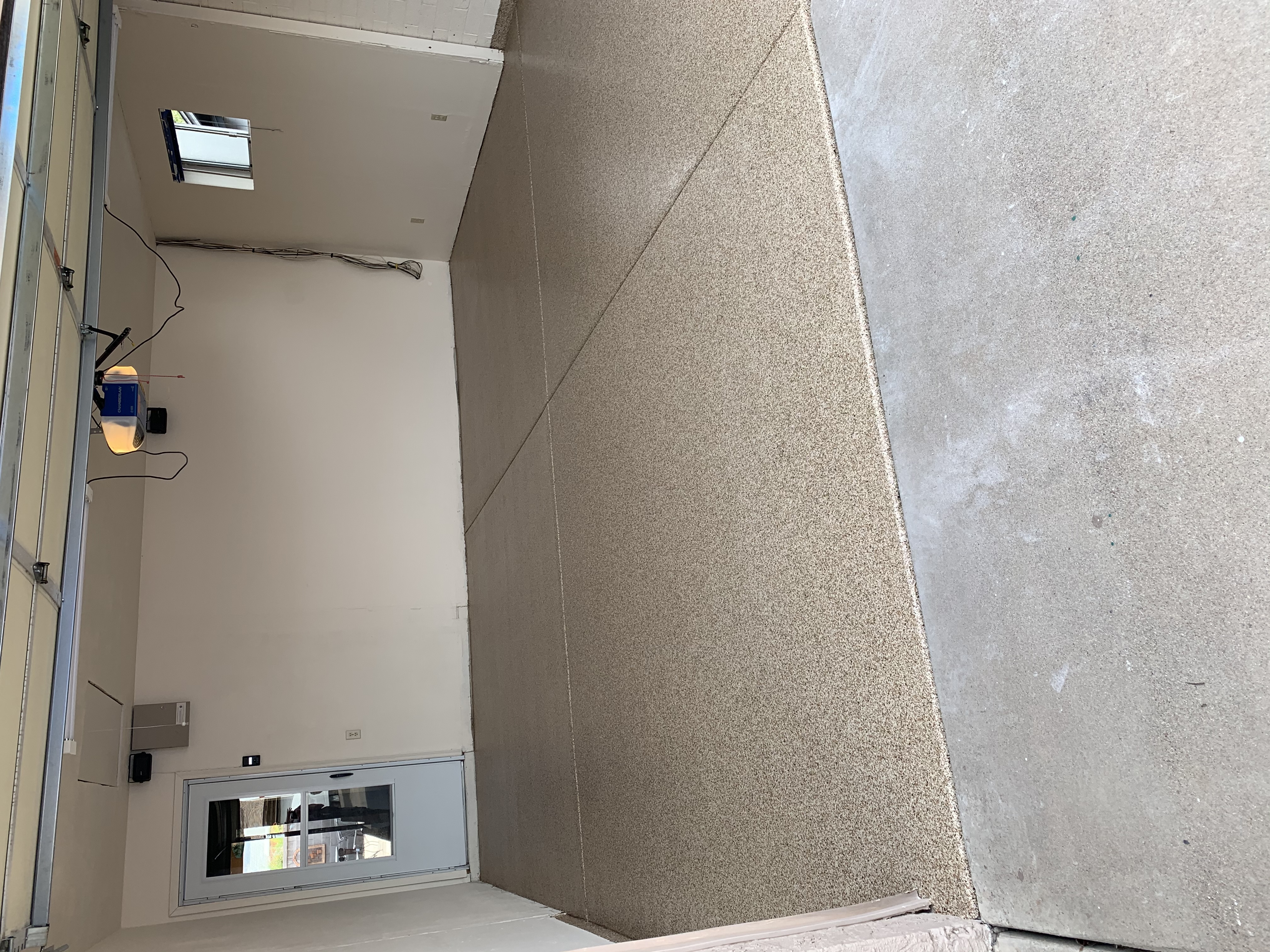Residential garage before floor coating bare concrete with garage door opener visible