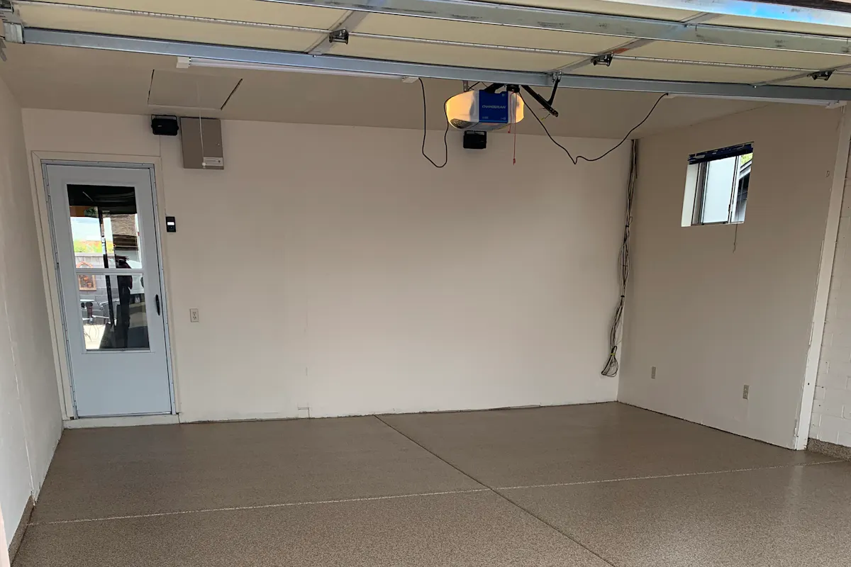 Residential garage before floor coating bare concrete with garage door opener visible