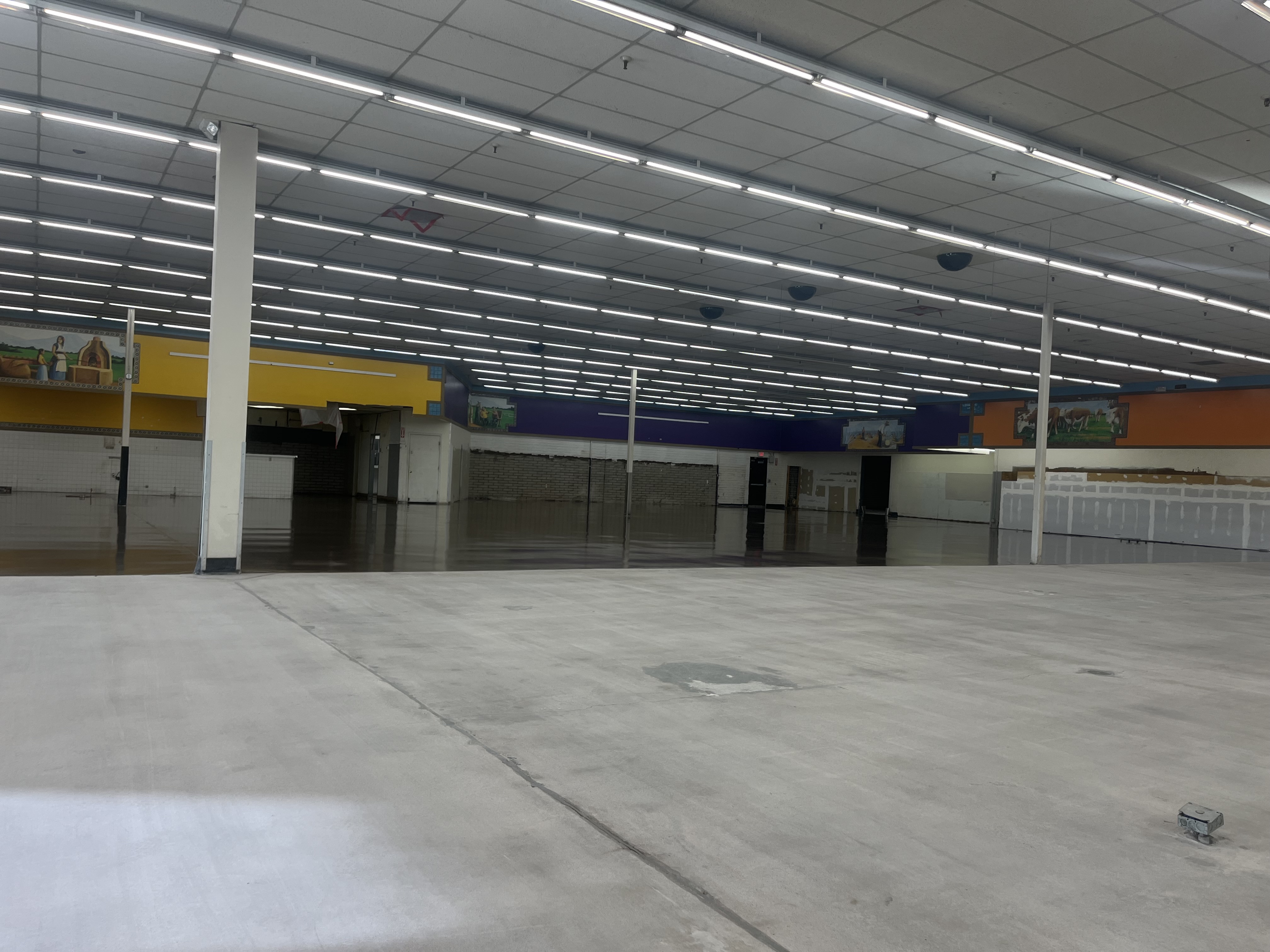 Commercial large retail space before coating bare concrete fluorescent lights colorful walls