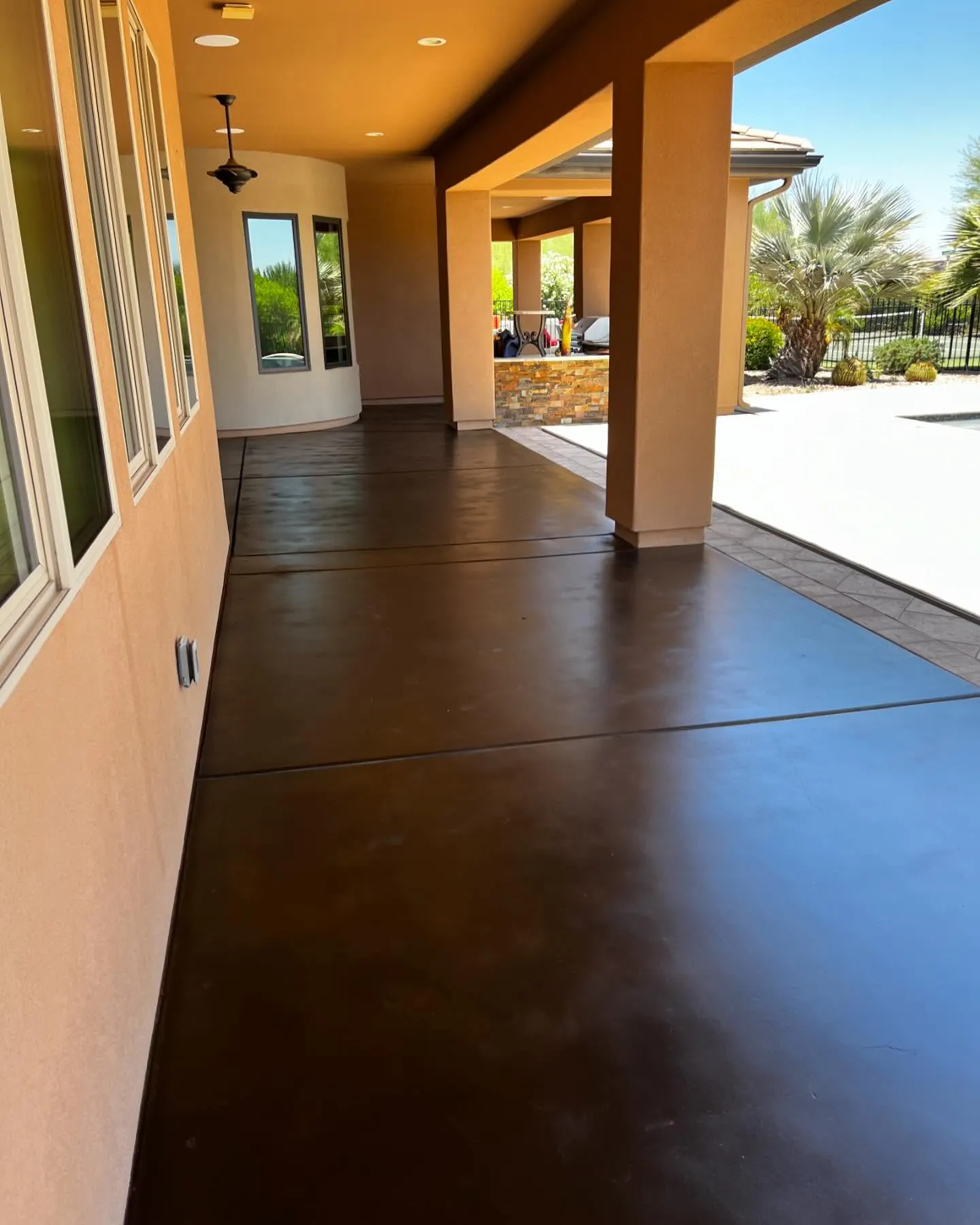 Residential covered patio with dark solid stained concrete coating at sunset