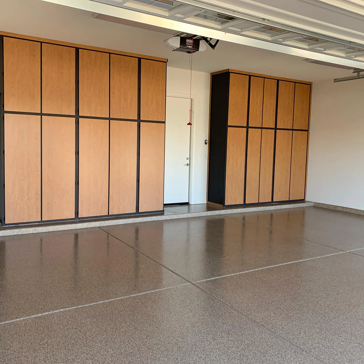 Residential garage with solid polyaspartic floor coating and large wooden cabinet doors