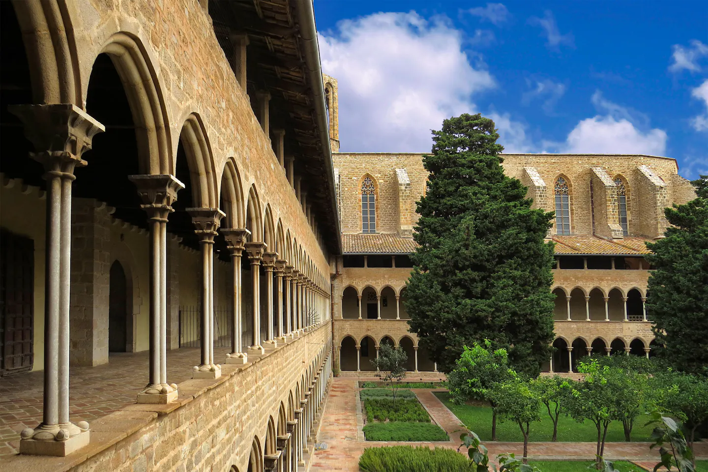 Gothic arcades and slender columns around a courtyard garden of orange trees in a Barcelona cloister