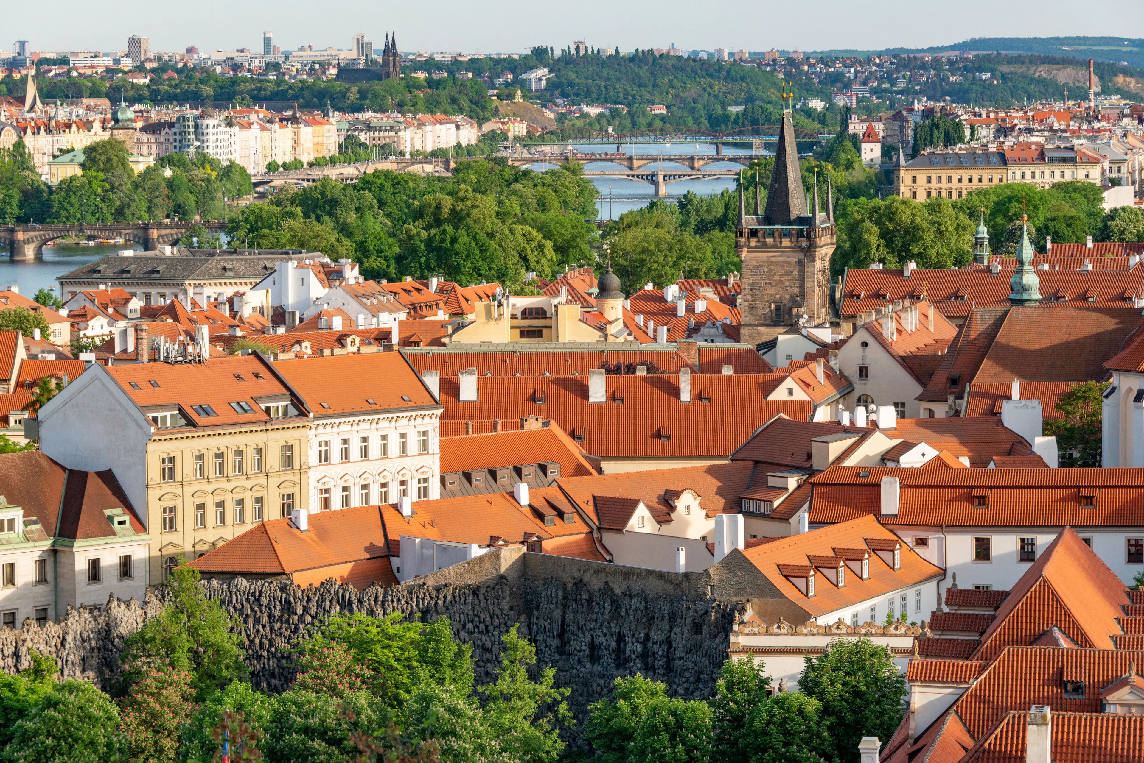 Prague's red rooftops and Lesser Town towers above the Vltava and its bridges on a clear summer day