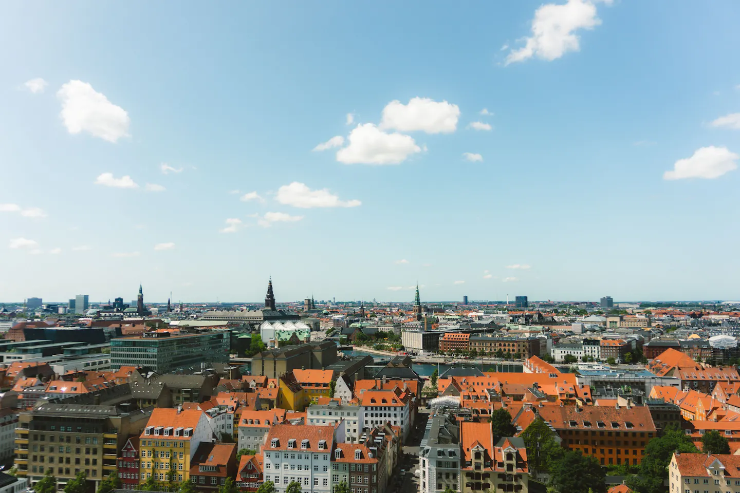 Copenhagen's orange rooftops and green copper spires under a bright summer sky