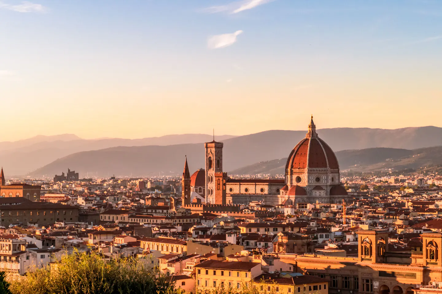 The red dome of Florence Cathedral and Giotto's campanile above the city's rooftops at sunset