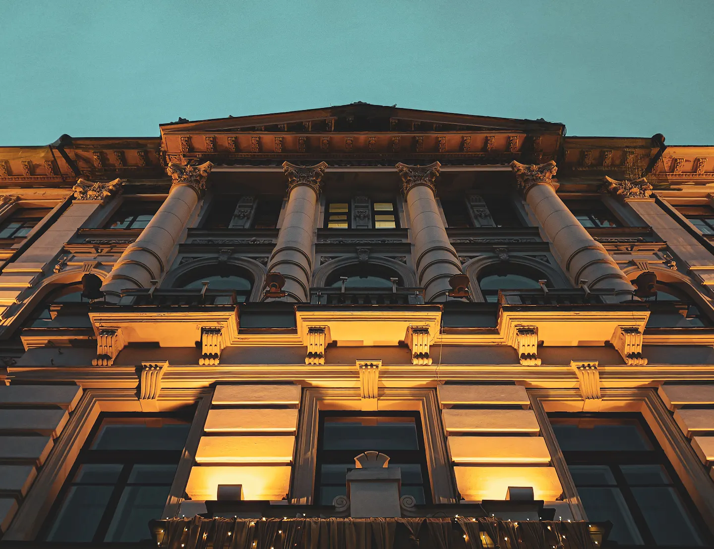 A columned historic facade in Vilnius lit warm gold against a deep teal evening sky