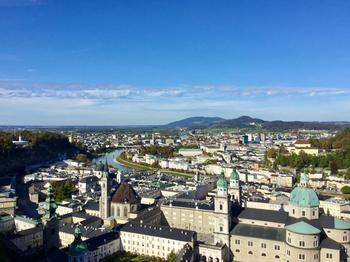 Salzburg's green domes and the Salzach river seen from the fortress, hills on the horizon