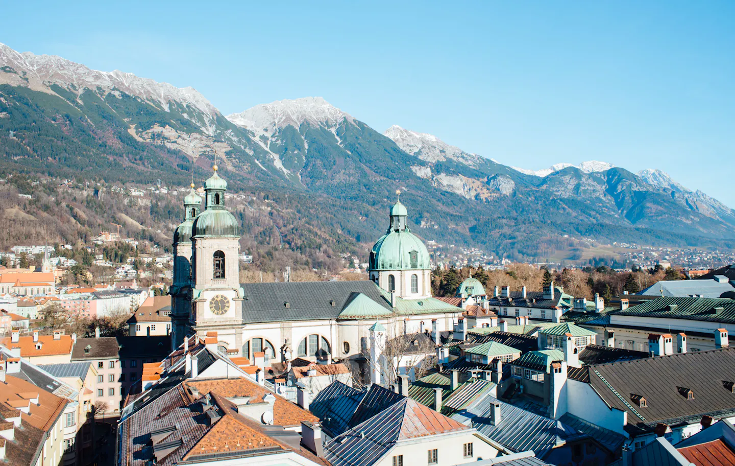 The domes of Innsbruck Cathedral among old-town rooftops below the snow-dusted Nordkette range