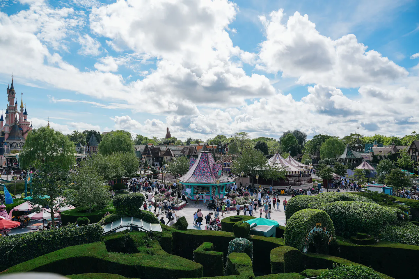 A wide view across landscaped Fantasyland at Disneyland Paris, with the castle at left