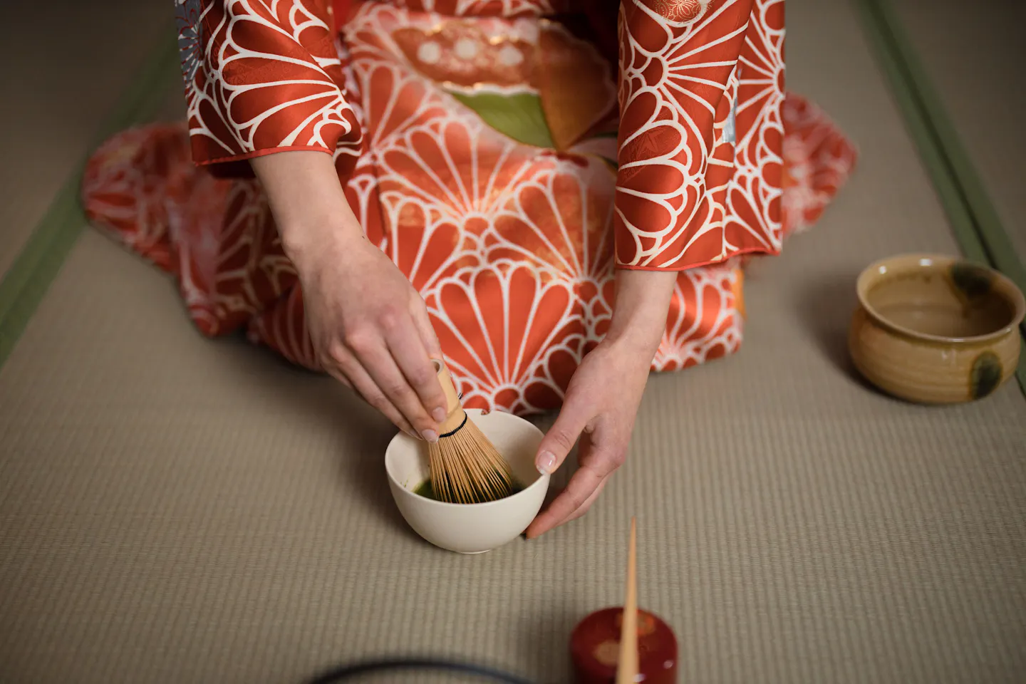 A person in a kimono preparing matcha in a tea ceremony