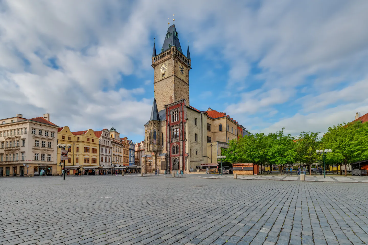The Old Town Hall tower above the cobbles of Prague's Old Town Square under tall clouds