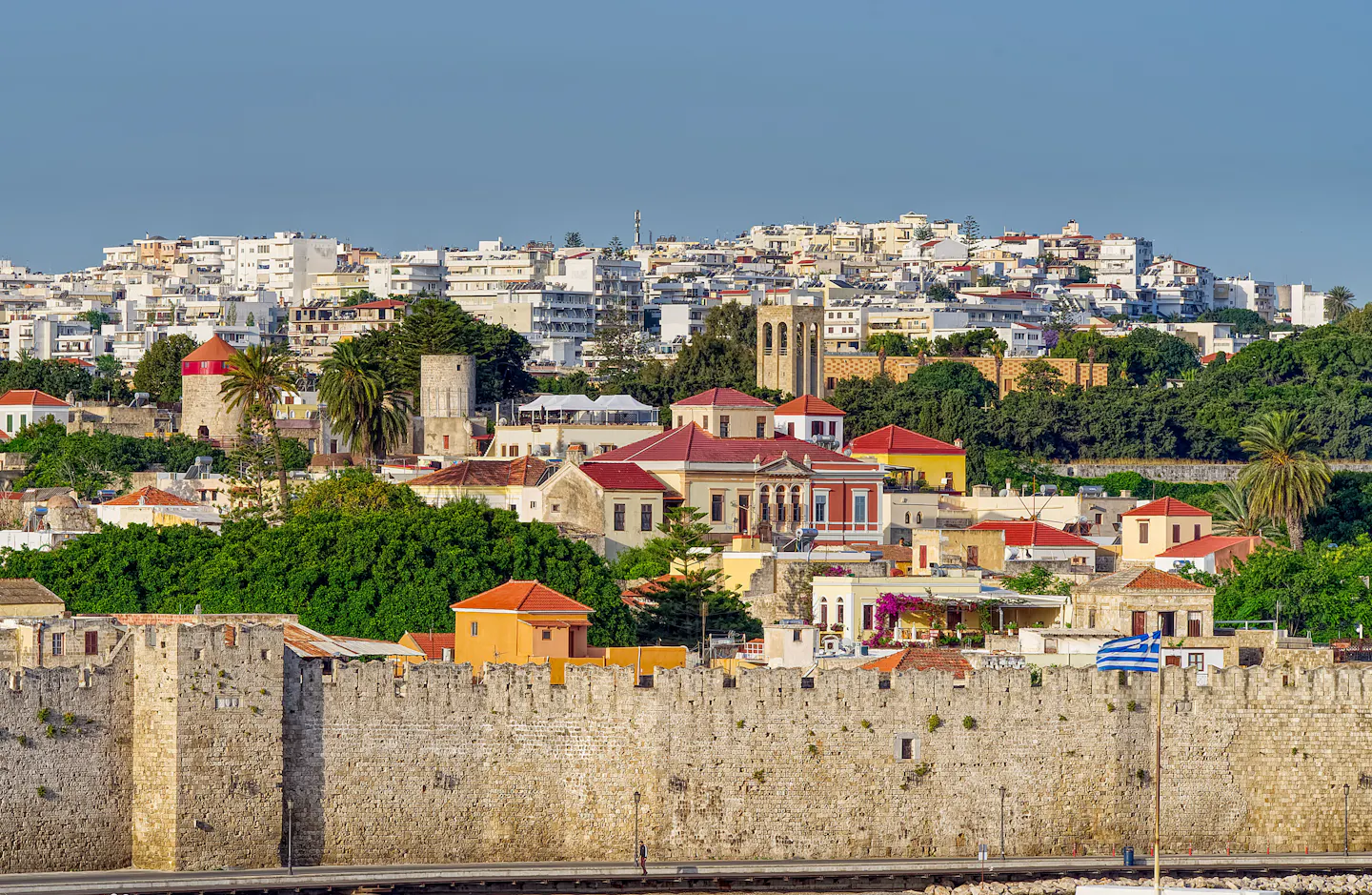 The medieval walls and tiled rooftops of Rhodes Old Town in warm evening light