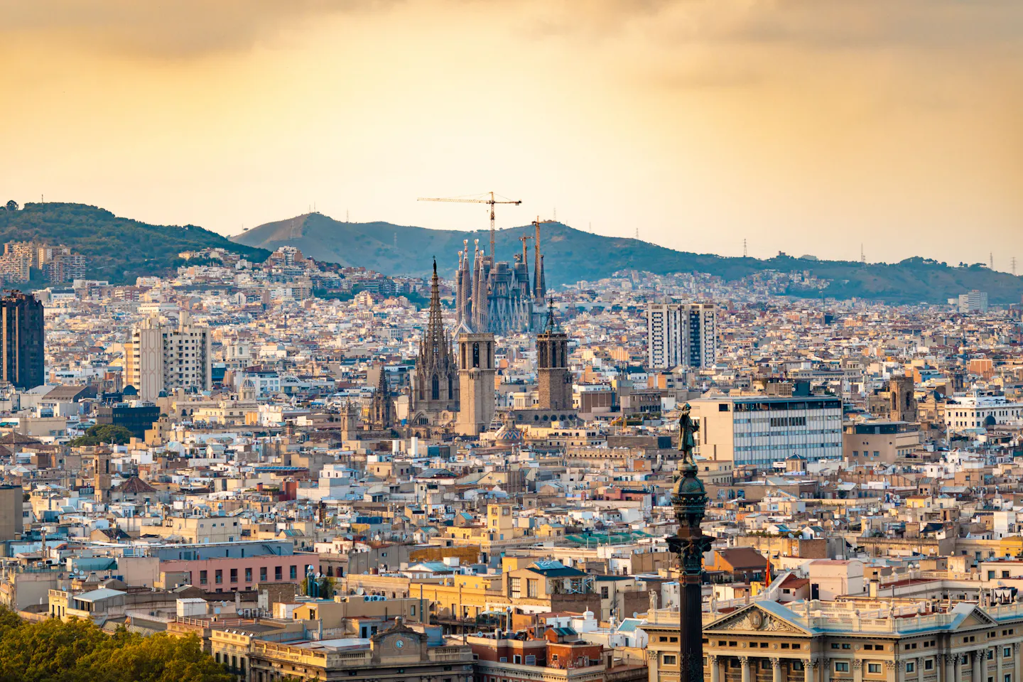 Barcelona rooftops at sunset with the Sagrada Familia and the cathedral rising above the city and hills beyond