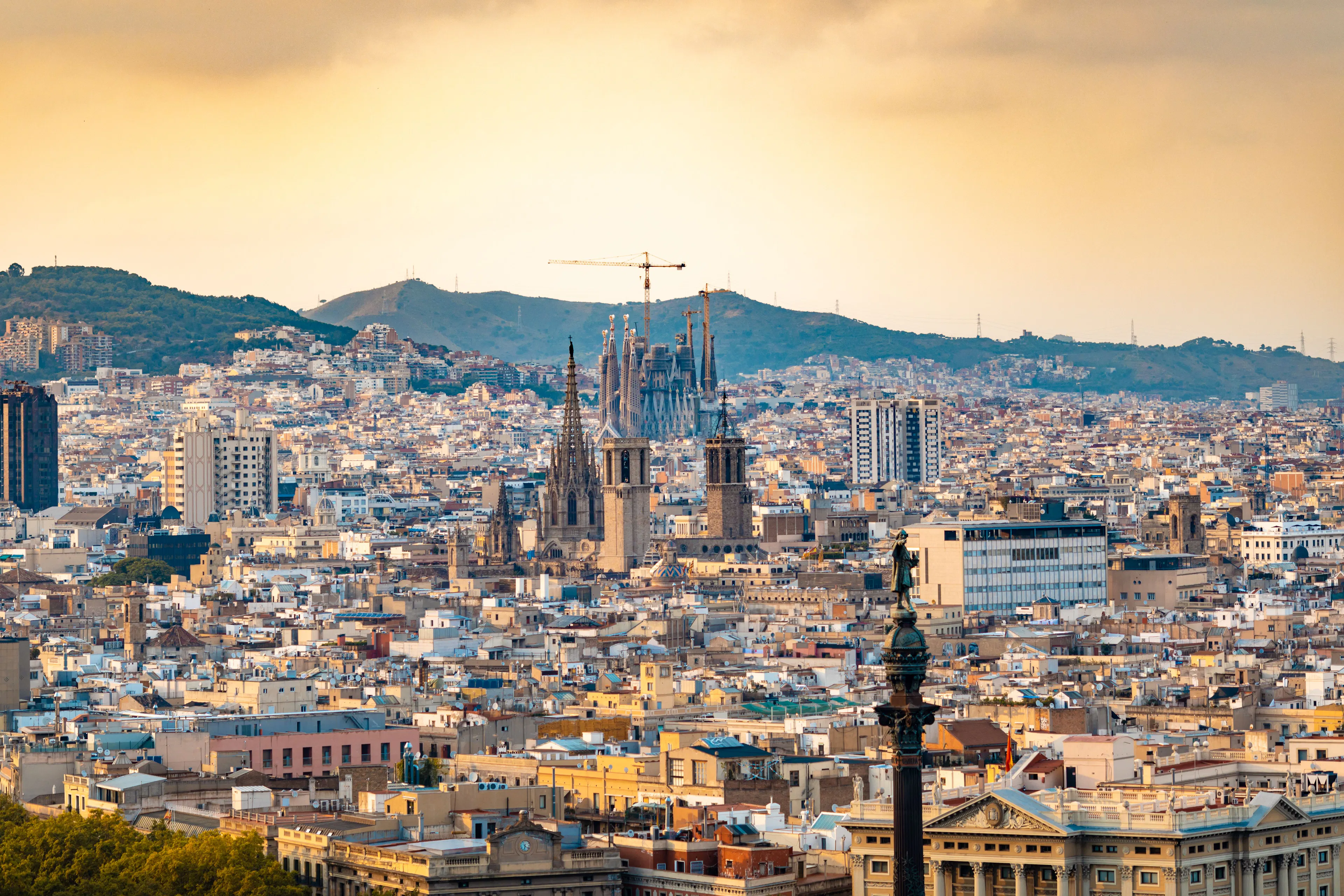 Barcelona rooftops at sunset with the Sagrada Familia and the cathedral rising above the city and hills beyond