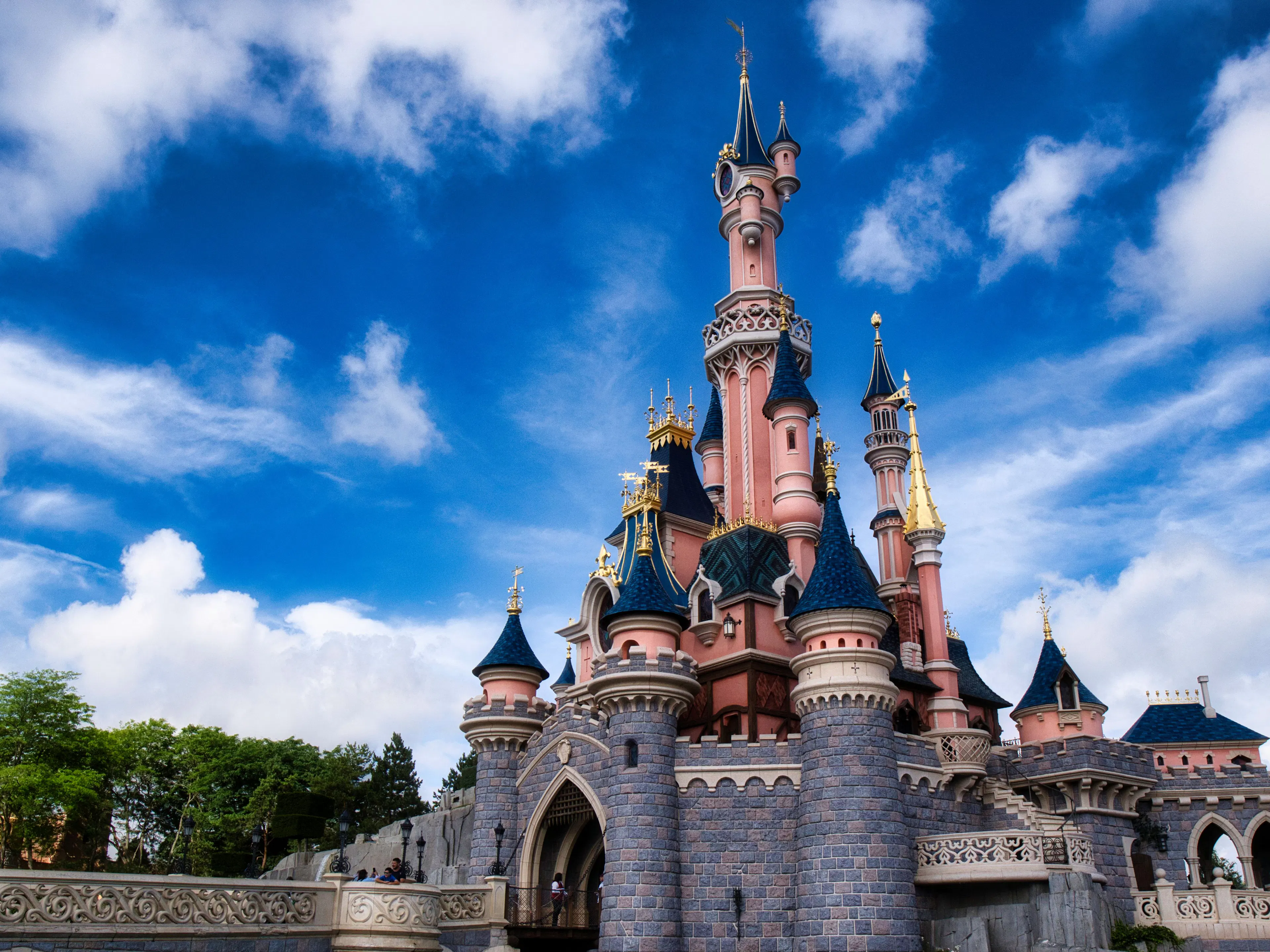 Sleeping Beauty Castle at Disneyland Paris, pink towers and blue turrets under a bright blue sky