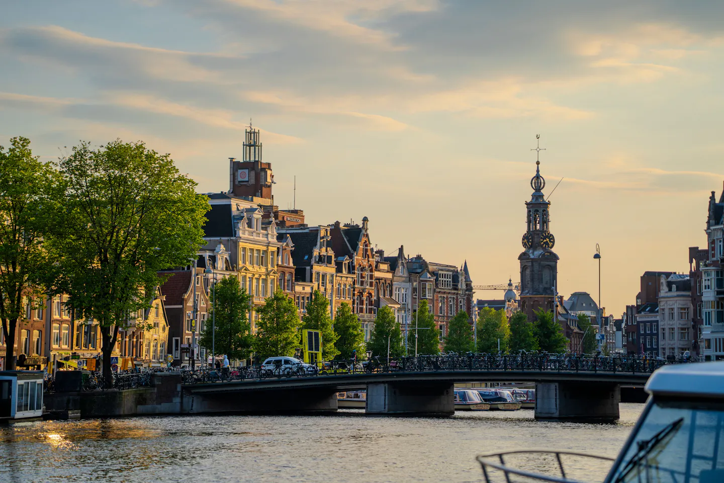 Golden evening light on Amsterdam's canal houses and the Munttoren tower beside the Amstel