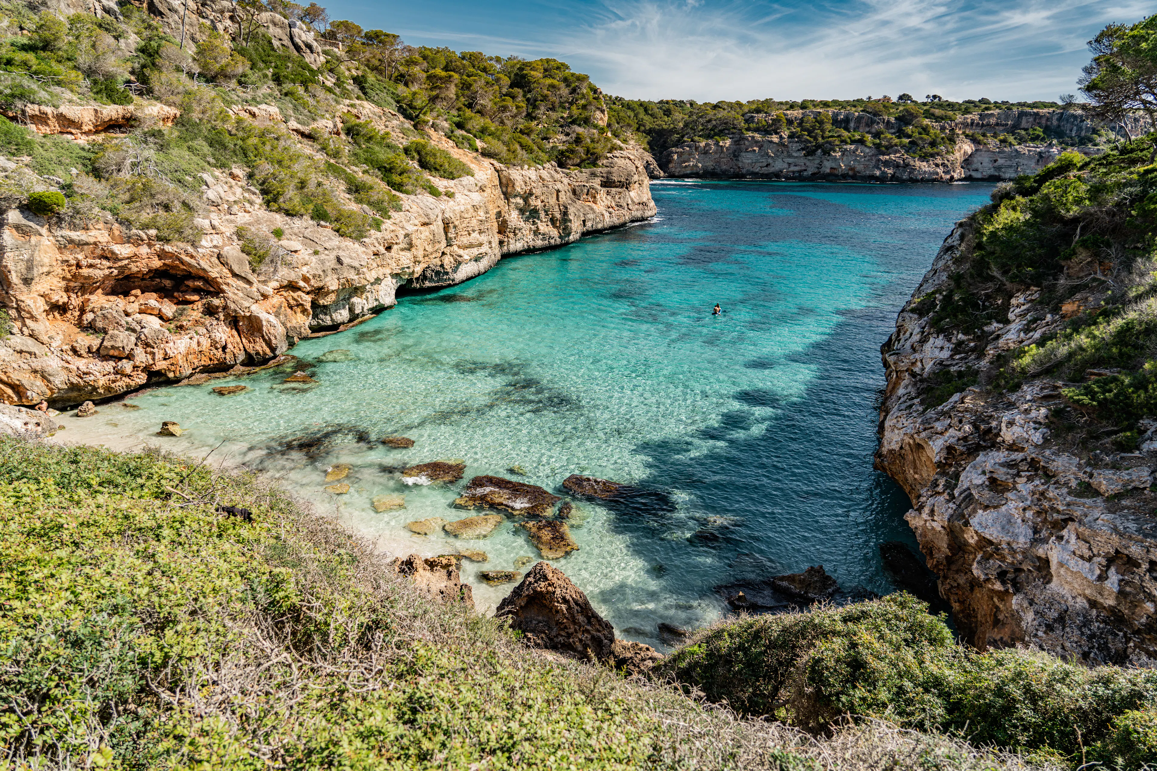 A turquoise cove enclosed by limestone cliffs and pines on the Mediterranean coast