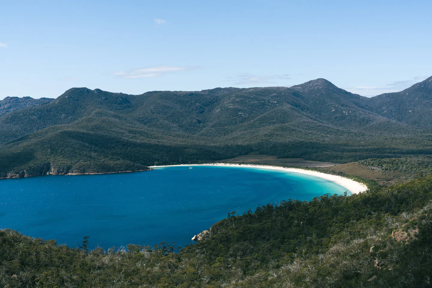 Aerial view of Wineglass Bay's turquoise water and forested hills in Tasmania