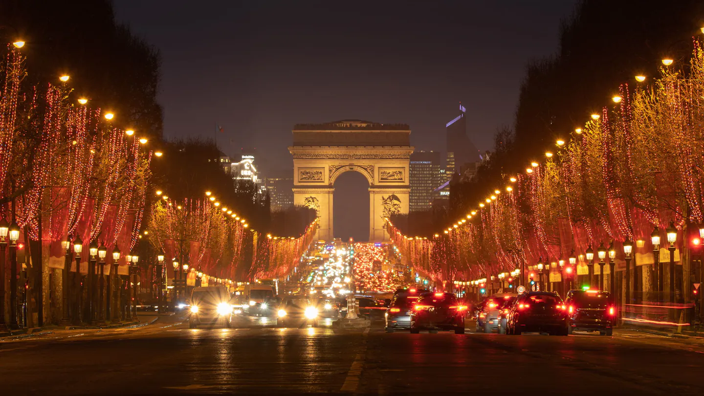 Christmas lights line the Champs-Élysées toward the Arc de Triomphe in Paris at night