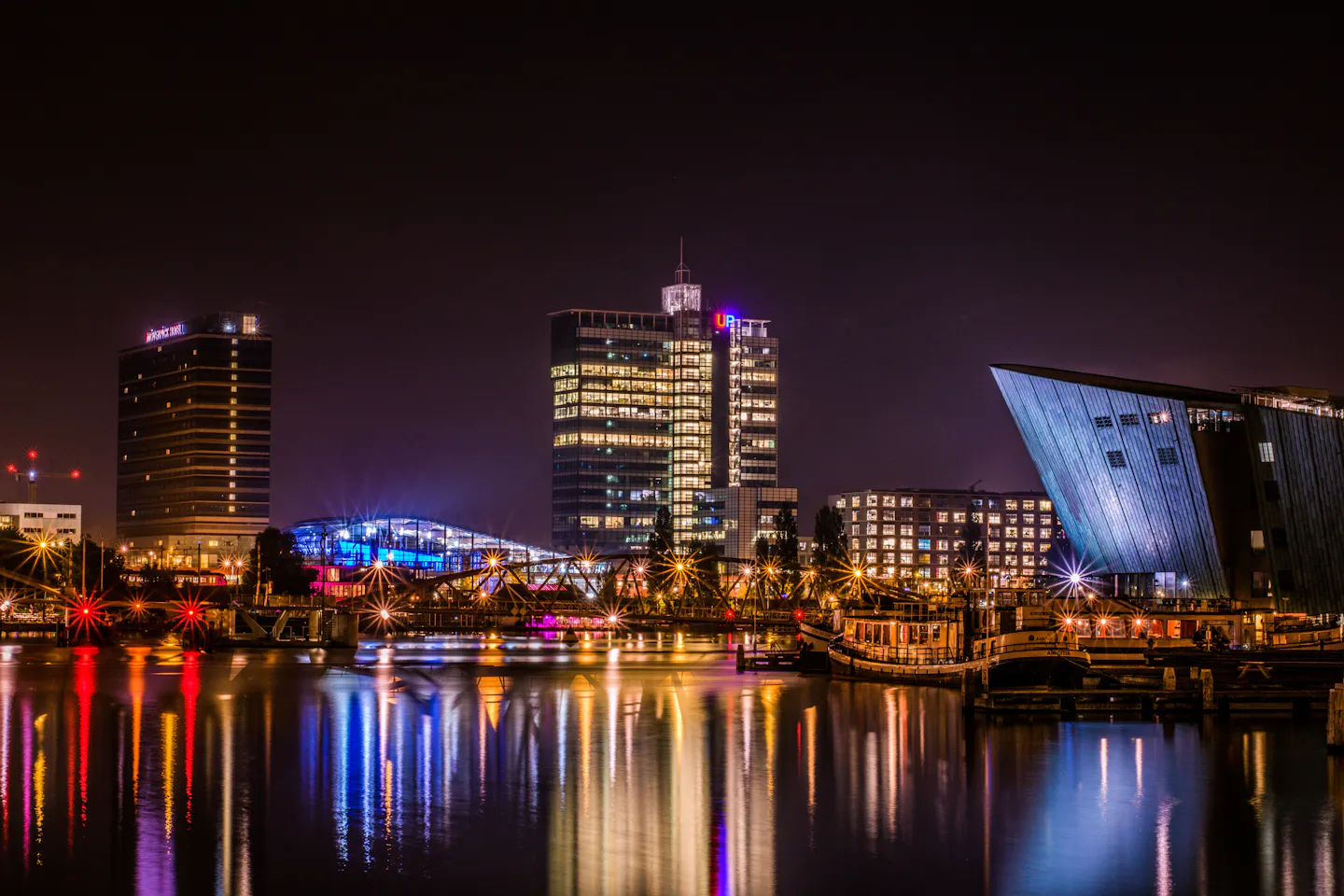 Coloured lights of Amsterdam's Oosterdok waterfront reflected in black water at night