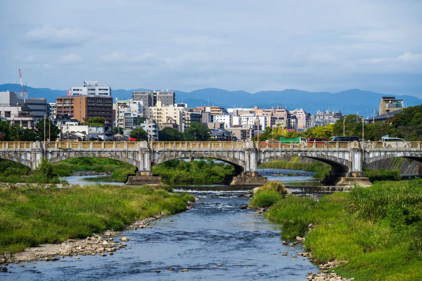 A river bridge and green mountains in a Japanese city