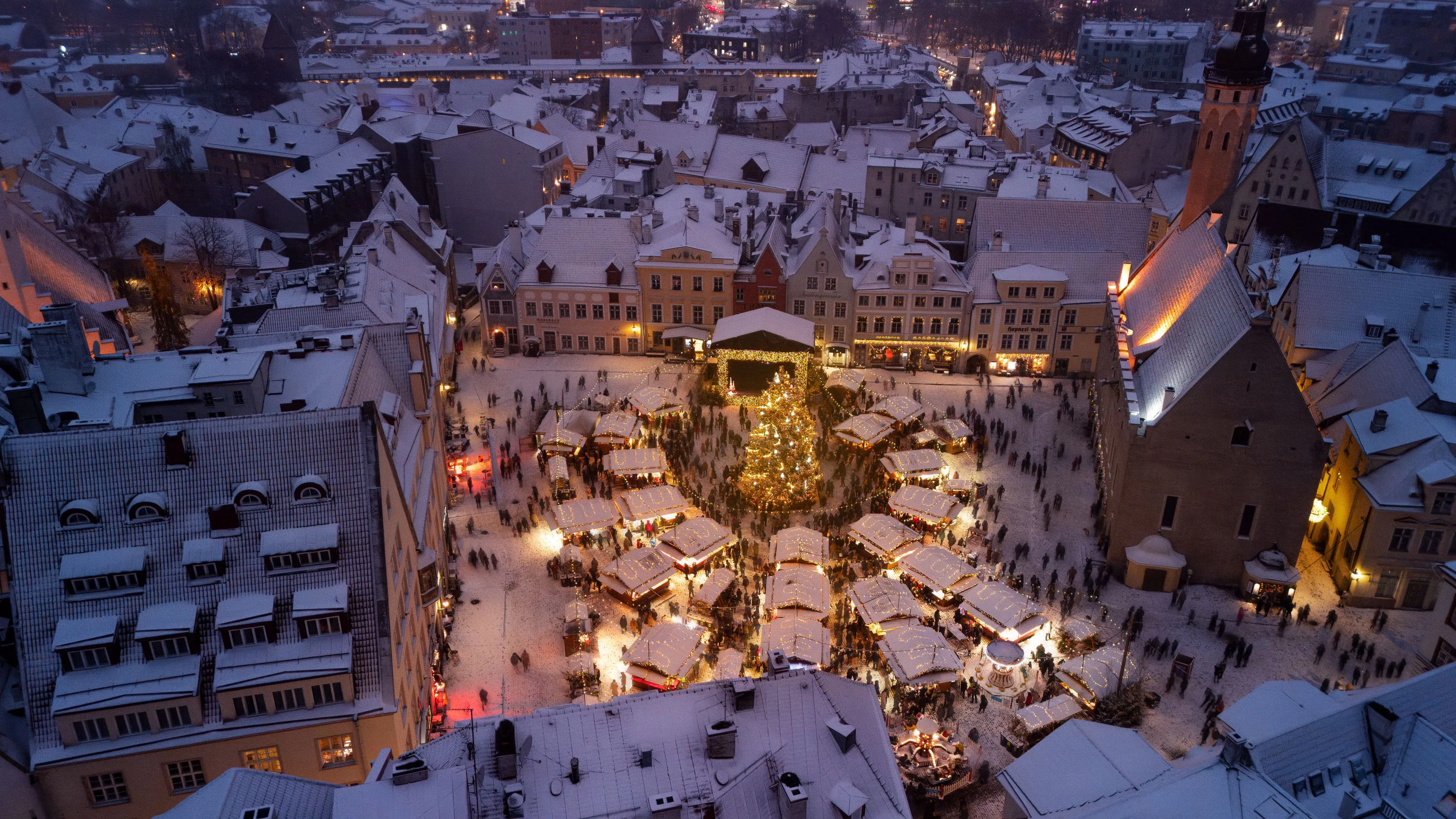Snow-covered Sibiu old-town square glowing with Christmas market lights in December.