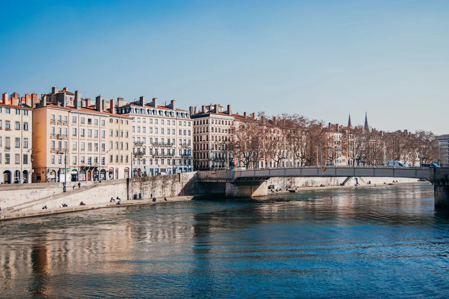 Tall pastel facades along the quays of the Saone in Lyon under a clear sky
