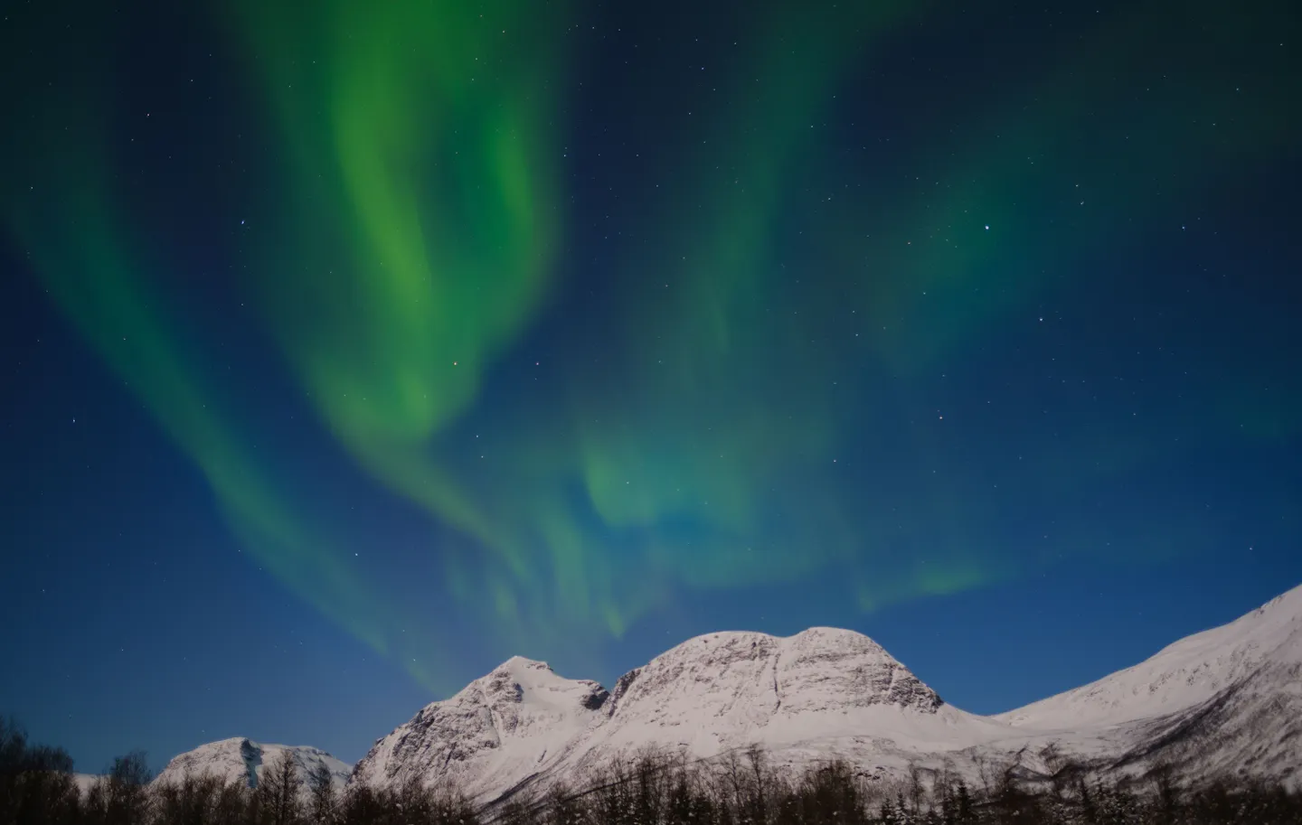 Northern lights over snow-covered mountains near Tromsø, Norway