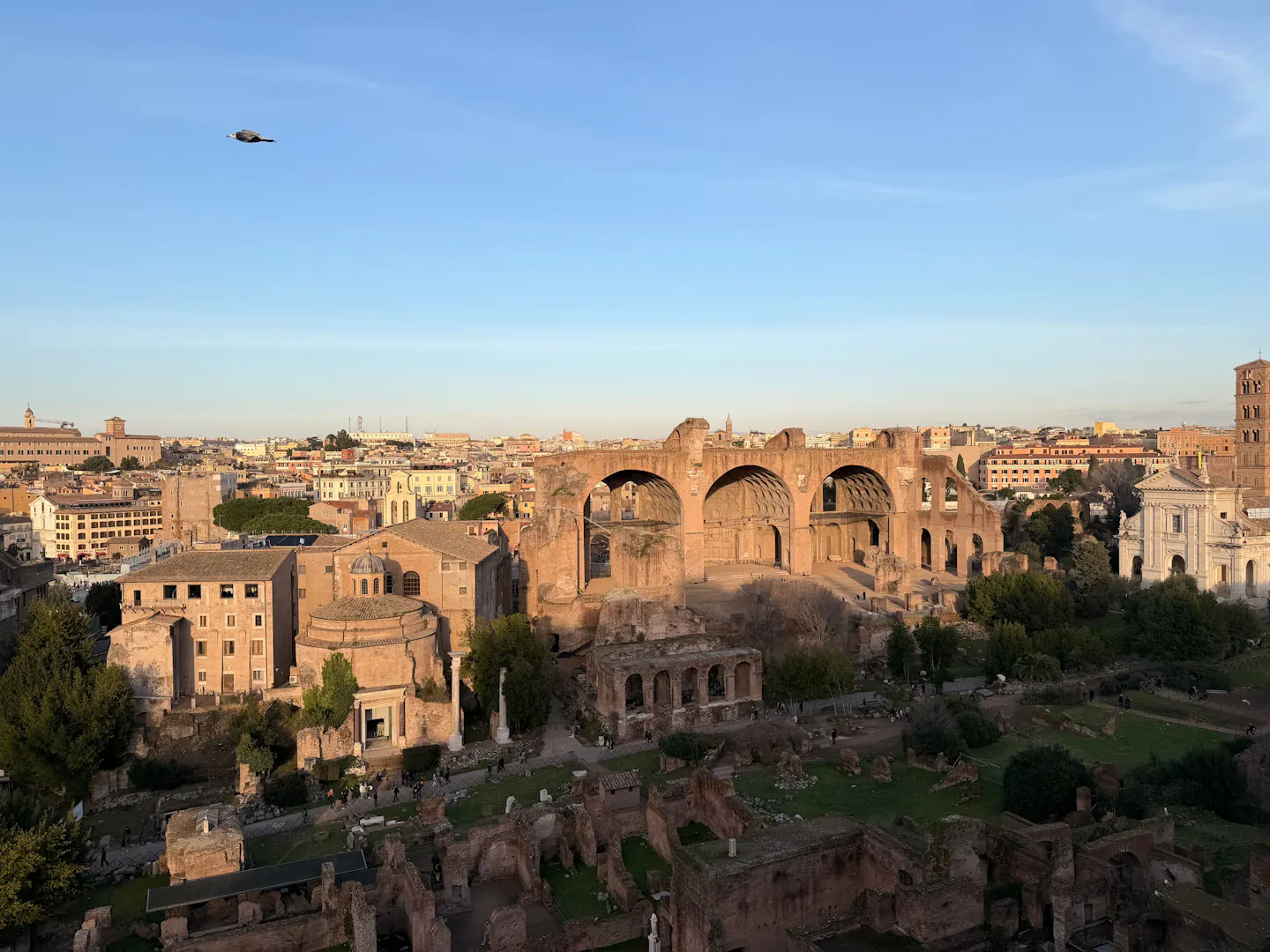 The three brick arches of the Basilica of Maxentius rising over the ruins of the Roman Forum in warm golden-hour light