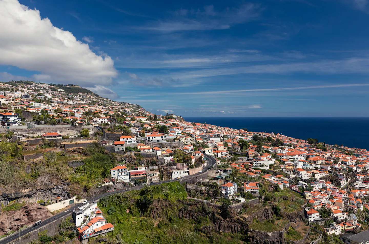 Red-tiled houses stepping down a green hillside to the blue Atlantic on Madeira's south coast