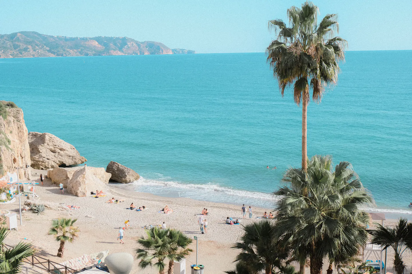Palm trees above a sandy cove and turquoise sea at Nerja on the Costa del Sol
